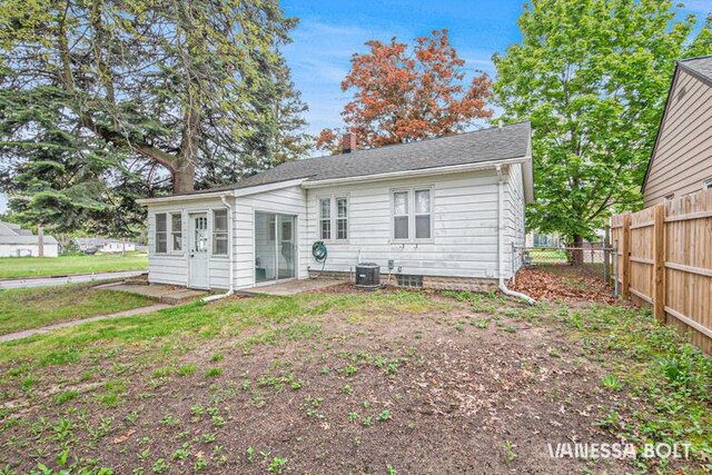 rear view of property featuring fence and central AC