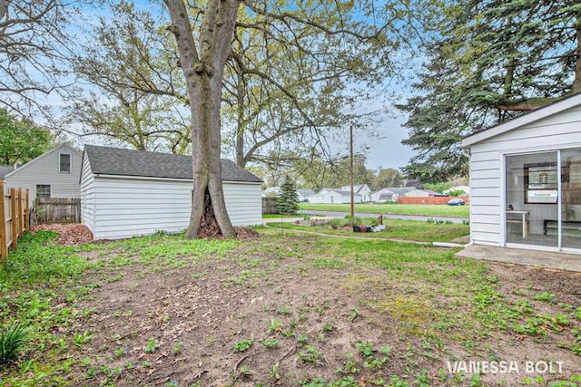 view of yard with fence, an outdoor structure, and a storage unit