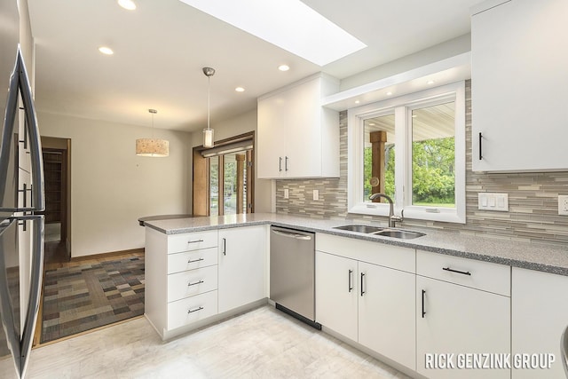 28 W 34th St, Holland, MI 49423 - kitchen featuring stainless steel appliances, a sink, a peninsula, white cabinetry, and tasteful backsplash