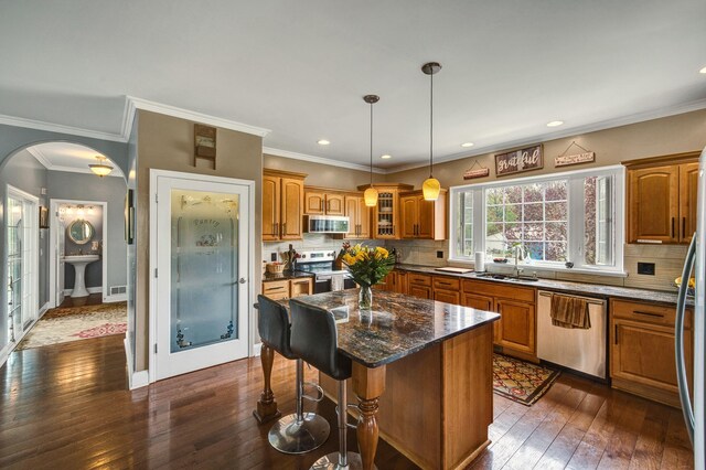 3725 S Creek Ln, Dryden, MI 48428 - kitchen with stainless steel appliances, a sink, brown cabinetry, a kitchen breakfast bar, and dark wood-type flooring