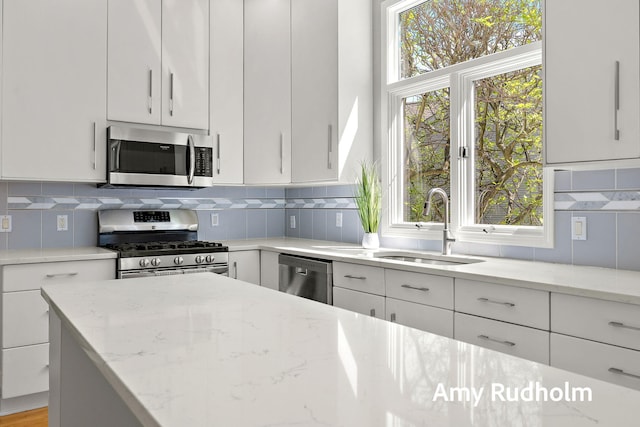 1995 W Glen Ct, Norton Shores, MI 49441 - kitchen featuring appliances with stainless steel finishes, a sink, light stone countertops, white cabinets, and tasteful backsplash