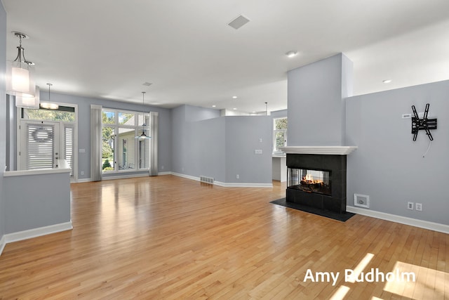 1995 W Glen Ct, Norton Shores, MI 49441 - unfurnished living room with light wood finished floors, baseboards, a multi sided fireplace, and recessed lighting