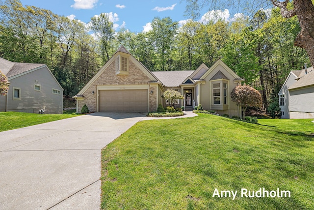 1995 W Glen Ct, Norton Shores, MI 49441 - view of front of house featuring an attached garage, concrete driveway, a front lawn, and brick siding