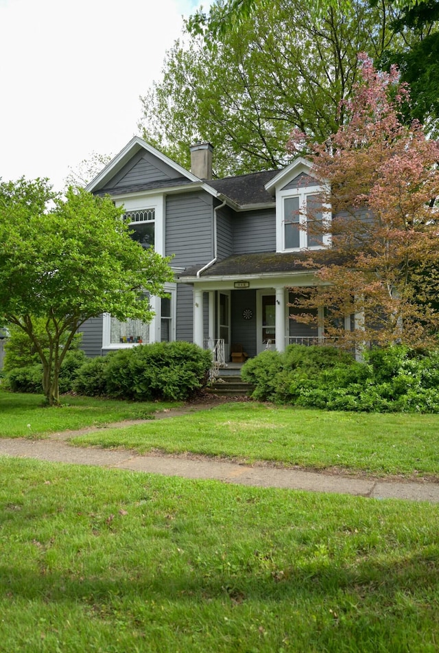 244 E Pearl St, Coldwater, MI 49036 - view of front of house featuring a chimney, covered porch, a front lawn, and a shingled roof