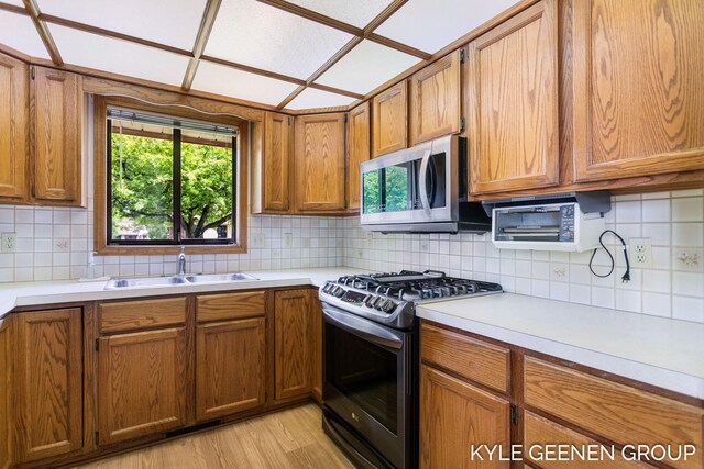 kitchen with appliances with stainless steel finishes, a sink, healthy amount of natural light, and light countertops
