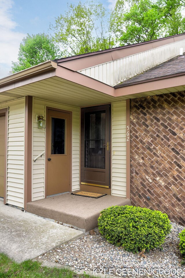 doorway to property featuring covered porch and brick siding