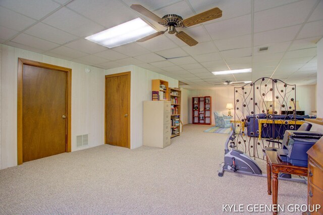 rec room with carpet floors, a paneled ceiling, a ceiling fan, and wood walls
