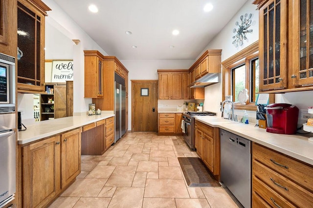 16431 Glassman Rd, Union Pier, MI 49129 - kitchen with high end appliances, under cabinet range hood, stone tile floors, a sink, and brown cabinets
