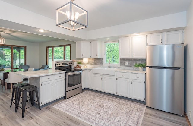 16436 45th Ave, Barryton, MI 49305 - kitchen featuring stainless steel appliances, a peninsula, a sink, white cabinetry, and light wood-style floors
