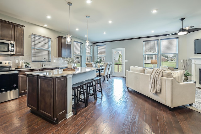 50305 Thatcher St, Canton, MI 48188 - kitchen featuring appliances with stainless steel finishes, dark brown cabinets, open floor plan, a center island, and a breakfast bar