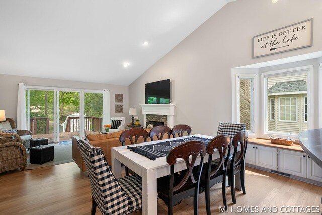 3760 Lakeshore Dr, Holland, MI 49424 - dining area with light wood-style floors, high vaulted ceiling, a stone fireplace, and recessed lighting