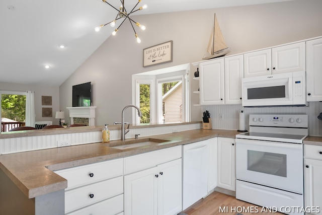 3760 Lakeshore Dr, Holland, MI 49424 - kitchen featuring white appliances, a sink, vaulted ceiling, a peninsula, and white cabinetry