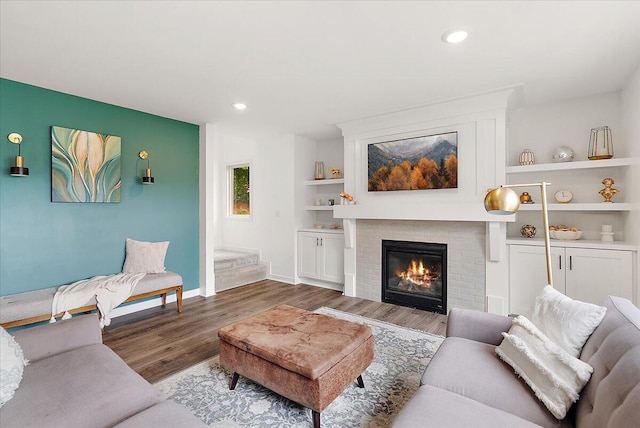 living area with wood finished floors, a fireplace, baseboards, recessed lighting, and built in shelves
