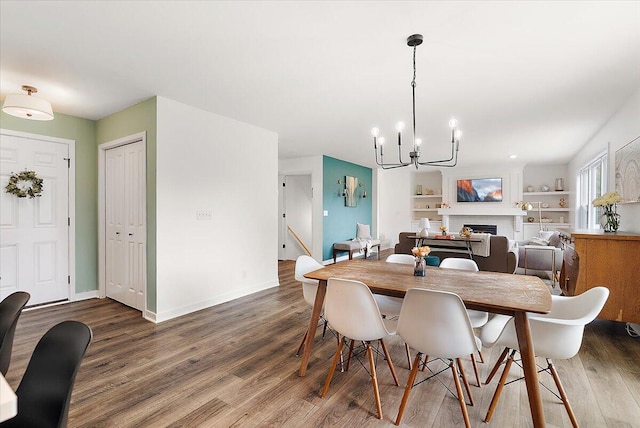 dining space with a chandelier, wood finished floors, a fireplace, and baseboards