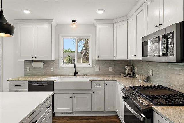 kitchen with stainless steel microwave, range with gas stovetop, a sink, light countertops, and decorative backsplash