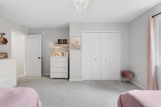 carpeted bedroom with a closet, baseboards, and a chandelier