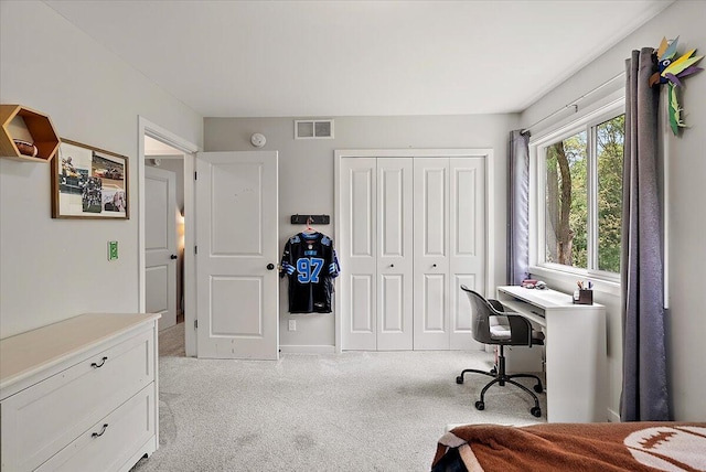carpeted bedroom with a closet and an office area