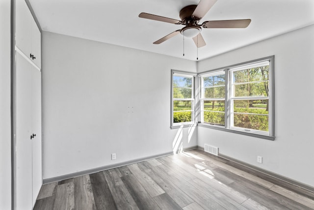 unfurnished bedroom featuring wood finished floors, baseboards, a ceiling fan, and a closet