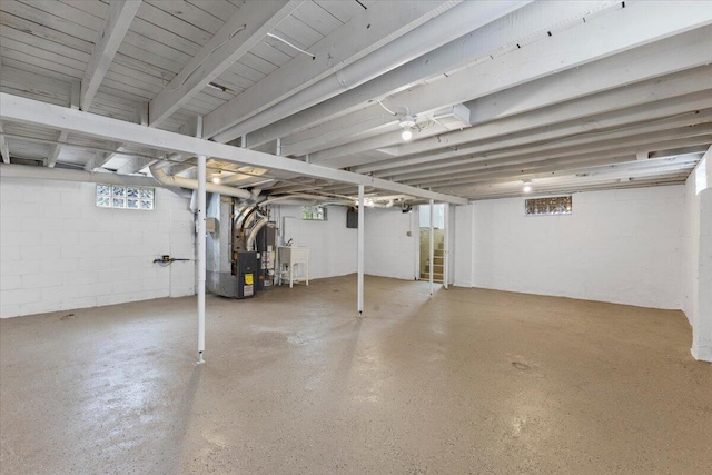below grade area featuring heating unit, concrete block wall, and a sink