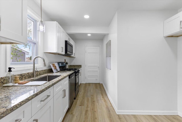 kitchen featuring white cabinetry, black range oven, light wood finished floors, light stone counters, and recessed lighting