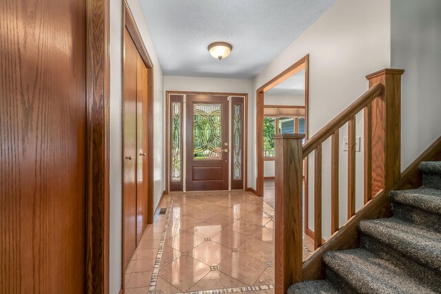 586 Schaeffer Dr, Coldwater, MI 49036 - foyer entrance with inlaid floor details, stairway, light tile patterned flooring, baseboards, and a textured ceiling