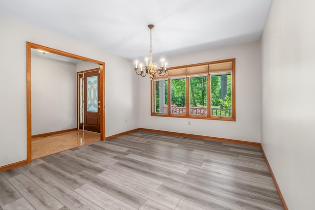 586 Schaeffer Dr, Coldwater, MI 49036 - unfurnished room with a chandelier, light wood-style floors, and baseboards