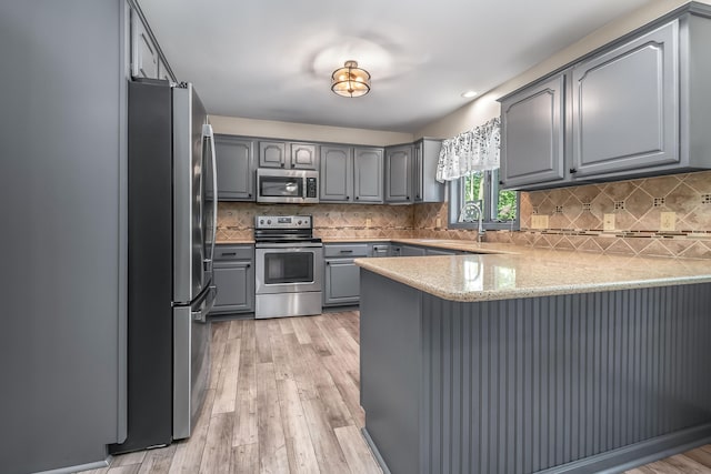 586 Schaeffer Dr, Coldwater, MI 49036 - kitchen featuring stainless steel appliances, gray cabinets, a peninsula, light wood-style flooring, and tasteful backsplash