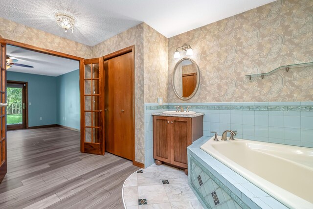 586 Schaeffer Dr, Coldwater, MI 49036 - bathroom with a bath, vanity, wallpapered walls, and wood finished floors