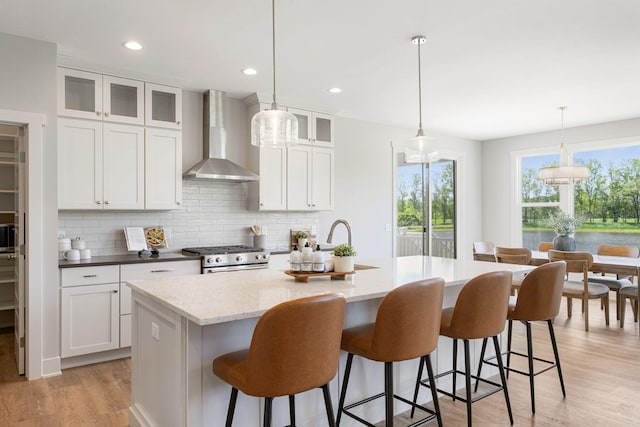 9156 Perry Ct Lot C, Lot C, Zeeland, MI 49464 - kitchen featuring wall chimney exhaust hood, high end stainless steel range oven, tasteful backsplash, a center island with sink, and light wood-style flooring