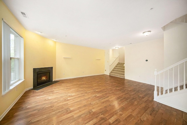 3197 Asher Rd, Ann Arbor, MI 48104 - unfurnished living room with stairs, light wood-style flooring, a lit fireplace, and baseboards