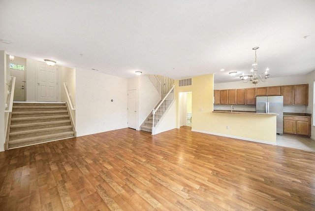 3197 Asher Rd, Ann Arbor, MI 48104 - unfurnished living room with stairs, a chandelier, light wood-type flooring, and baseboards