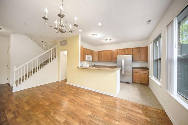 3197 Asher Rd, Ann Arbor, MI 48104 - kitchen featuring freestanding refrigerator, white microwave, light wood-style flooring, a chandelier, and recessed lighting