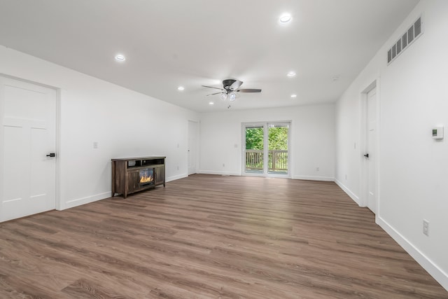 611 River Rd, Marshall, MI 49068 - unfurnished living room featuring ceiling fan, recessed lighting, wood finished floors, a lit fireplace, and baseboards