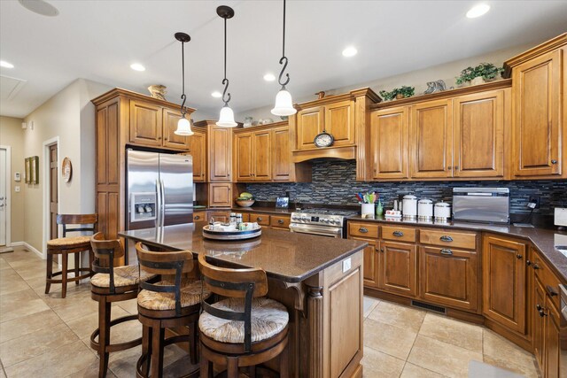 1259 Rose Dr, Niles, MI 49120 - kitchen with appliances with stainless steel finishes, brown cabinetry, backsplash, light tile patterned flooring, and a kitchen bar