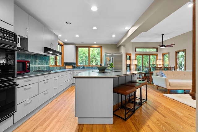 1711 Morton Ave, Ann Arbor, MI 48104 - kitchen with stainless steel appliances, dark countertops, a center island, a kitchen breakfast bar, and recessed lighting