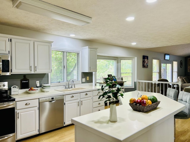 5335 Heathrow Ave, Kalamazoo, MI 49009 - kitchen featuring appliances with stainless steel finishes, a sink, open floor plan, light wood finished floors, and a textured ceiling