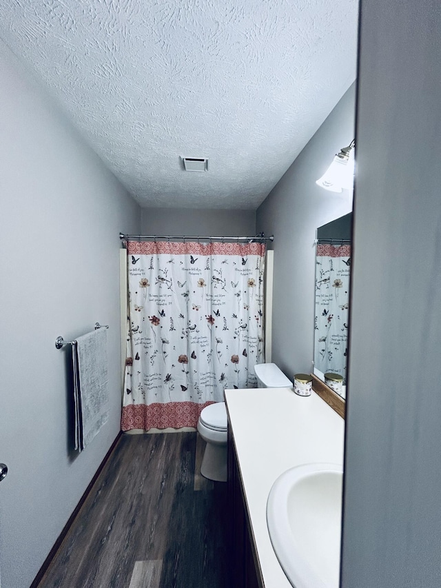 5335 Heathrow Ave, Kalamazoo, MI 49009 - bathroom featuring wood finished floors, vanity, toilet, a textured ceiling, and a shower with shower curtain