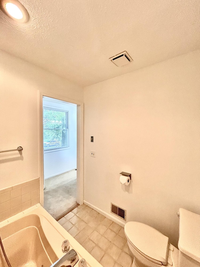 5335 Heathrow Ave, Kalamazoo, MI 49009 - bathroom with toilet, a garden tub, a textured ceiling, and baseboards
