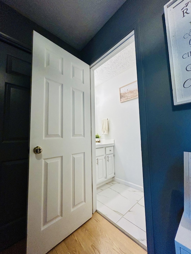 5335 Heathrow Ave, Kalamazoo, MI 49009 - bathroom featuring a textured ceiling, baseboards, vanity, and marble finish flooring