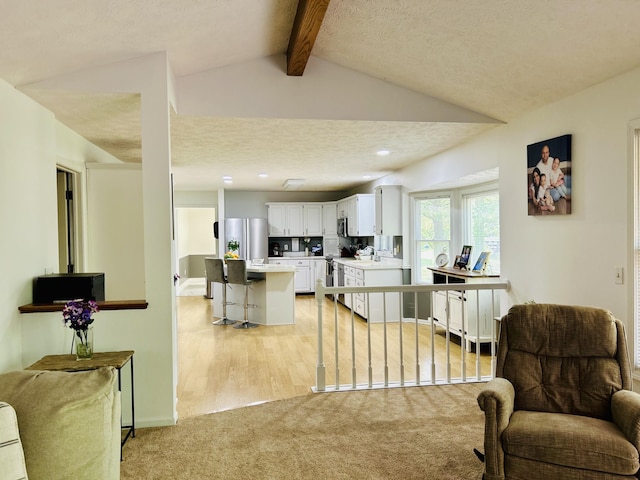 5335 Heathrow Ave, Kalamazoo, MI 49009 - kitchen with stainless steel fridge, a kitchen bar, open floor plan, light countertops, and white cabinetry