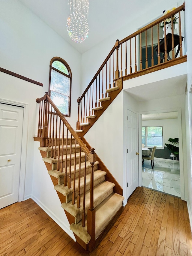 5335 Heathrow Ave, Kalamazoo, MI 49009 - stairway featuring wood-type flooring, a chandelier, a high ceiling, and baseboards