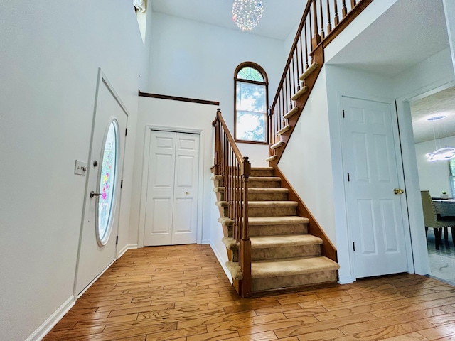 5335 Heathrow Ave, Kalamazoo, MI 49009 - entrance foyer featuring light wood-type flooring, stairs, a chandelier, and a towering ceiling