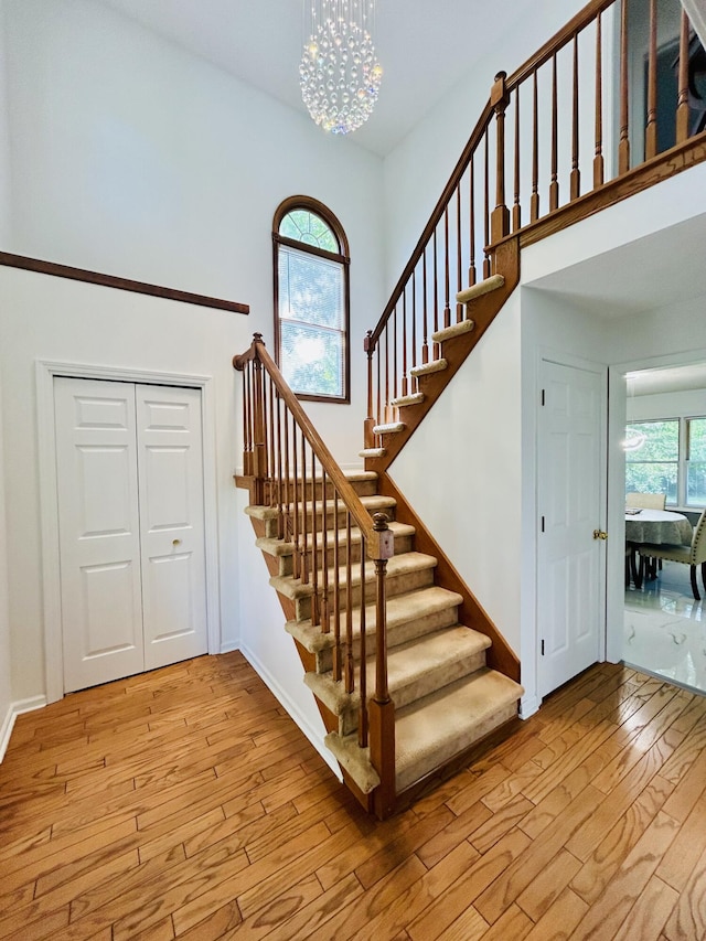 5335 Heathrow Ave, Kalamazoo, MI 49009 - stairway featuring wood-type flooring, a chandelier, baseboards, and a towering ceiling