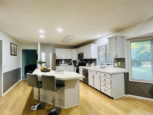 5335 Heathrow Ave, Kalamazoo, MI 49009 - kitchen featuring stainless steel appliances, a sink, light wood-style flooring, a center island, and white cabinetry