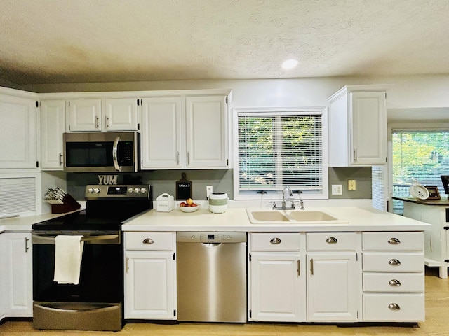 5335 Heathrow Ave, Kalamazoo, MI 49009 - kitchen with stainless steel appliances, a sink, white cabinetry, light countertops, and a textured ceiling