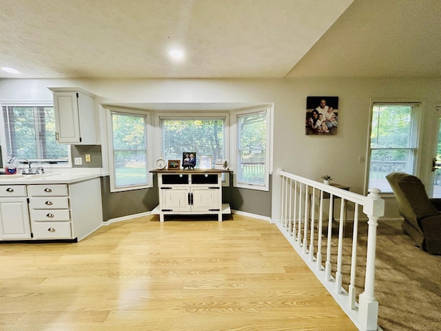 5335 Heathrow Ave, Kalamazoo, MI 49009 - kitchen with light wood finished floors, white cabinetry, light countertops, plenty of natural light, and a textured ceiling