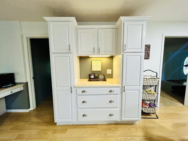 5335 Heathrow Ave, Kalamazoo, MI 49009 - kitchen with light wood-style flooring, white cabinetry, light countertops, and baseboards