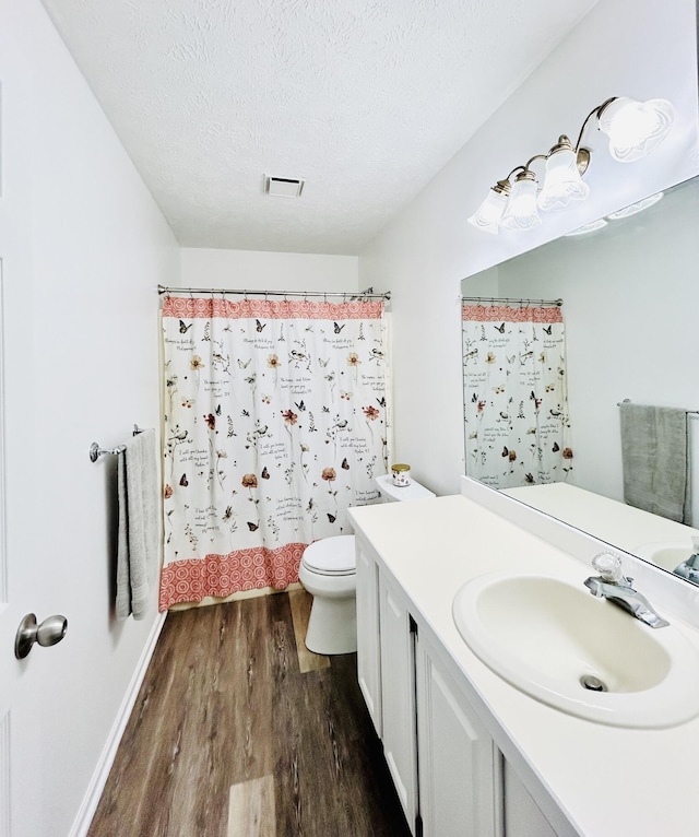 5335 Heathrow Ave, Kalamazoo, MI 49009 - bathroom with wood finished floors, toilet, vanity, a textured ceiling, and baseboards