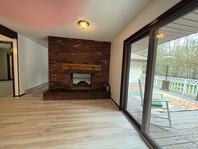 6035 W Trails End Rd, Ludington, MI 49431 - unfurnished living room featuring baseboard heating, wood finished floors, a textured ceiling, baseboards, and a fireplace