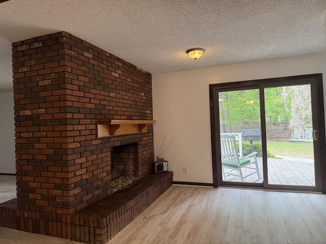 6035 W Trails End Rd, Ludington, MI 49431 - unfurnished living room with a textured ceiling, wood finished floors, a brick fireplace, and baseboards